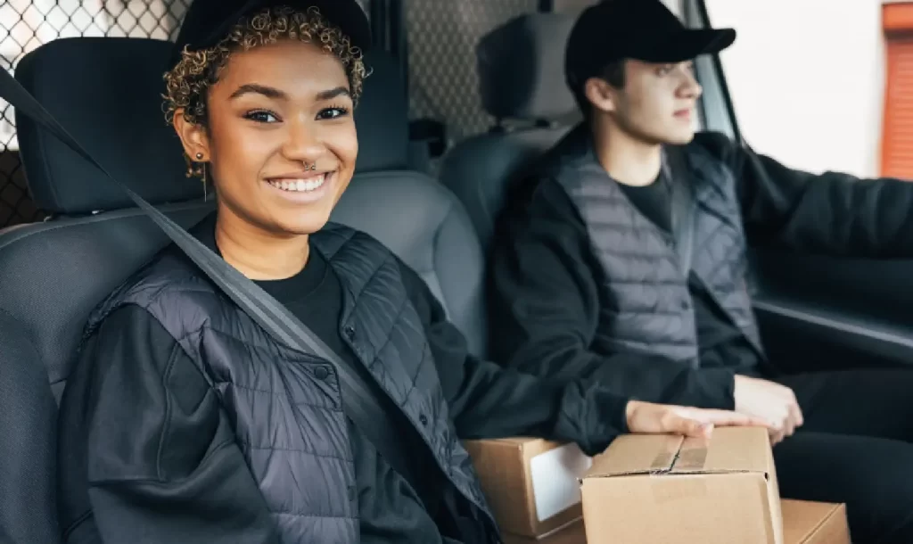 A man and a woman sit in the front seat of a box truck, discussing box truck financing options for their business expansion